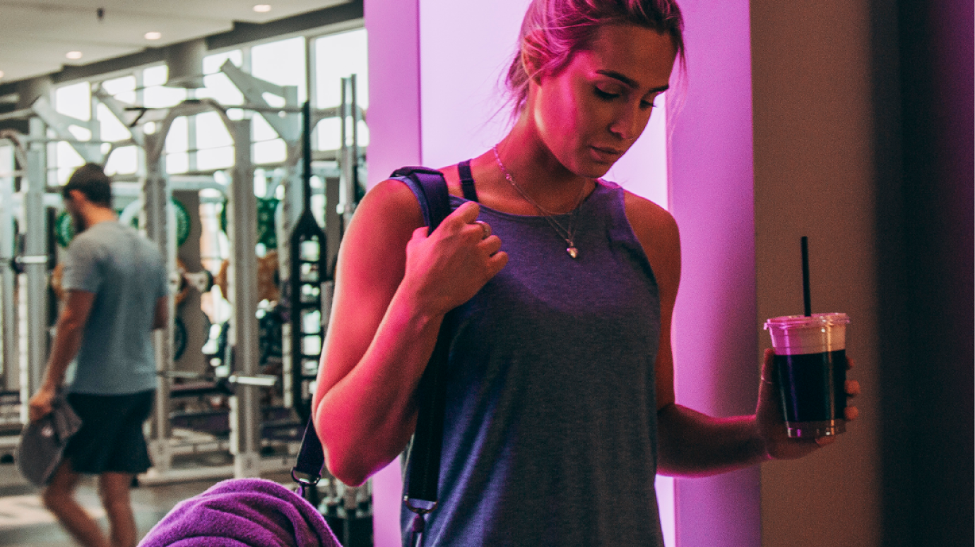 Woman is pictured with her gym bag under pink lighting