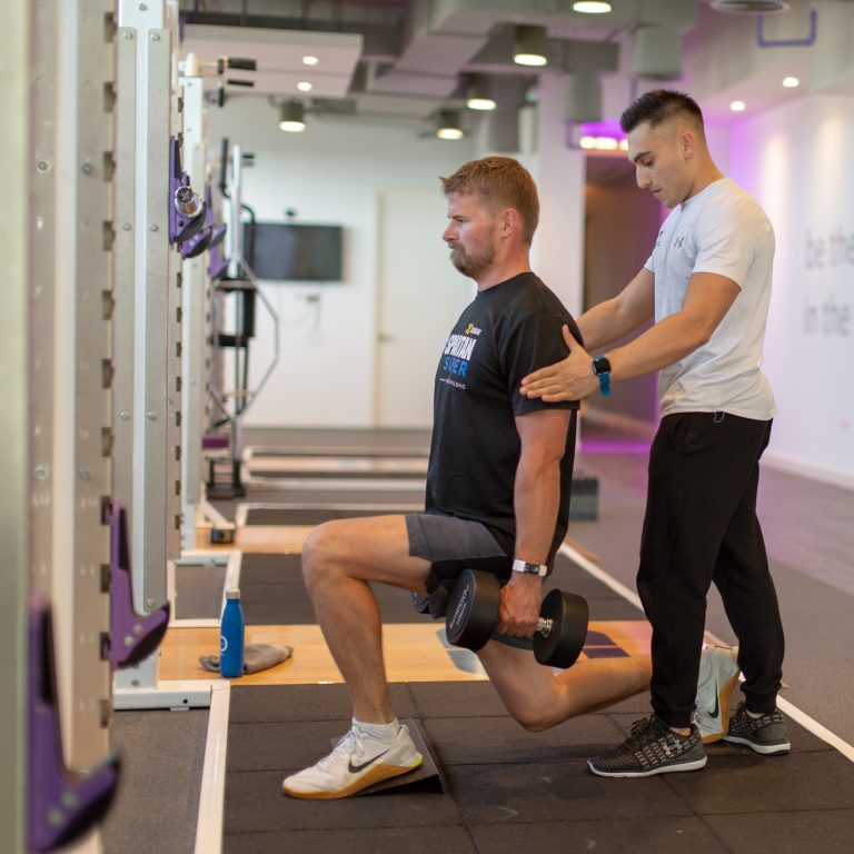 member doing split squats with trainer